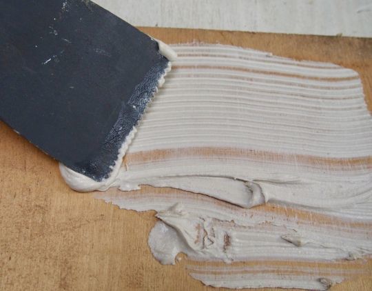 La colle s'applique à la spatule crantée