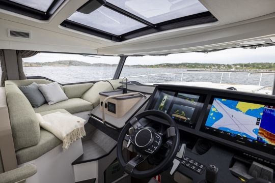 Le poste de pilotage du Nimbus 495 Flybridge est à proximité d'un petit coin salon cocooning pour tenir compagnie au pilote