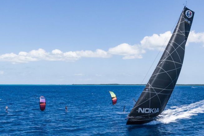 IMOCA Hugo Boss racing against two kitesurfers